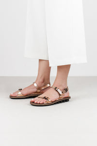 Trippen Slender copper metallic leather sandal with adjustable toe, instep, and heel buckle straps, two-tone footbed, and rubber sole, handmade in Germany. Angled lifestyle shot